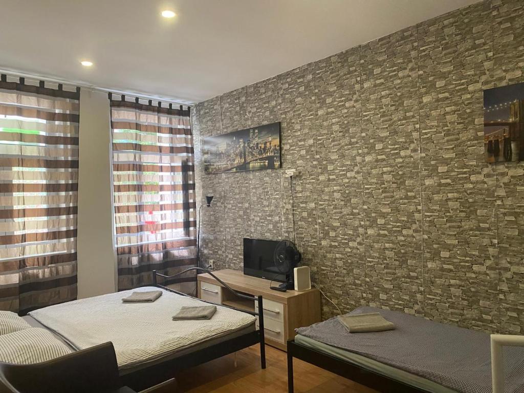 a room with two beds and a tv on a brick wall at Flat in Center Teplice in Teplice