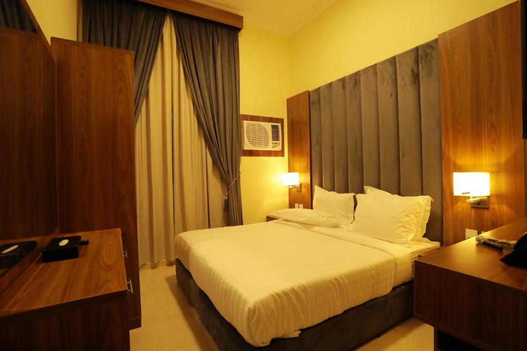 una camera da letto con un letto grande con testiera in legno di منازل الحساء للشقق الفندقية a Al Hofuf