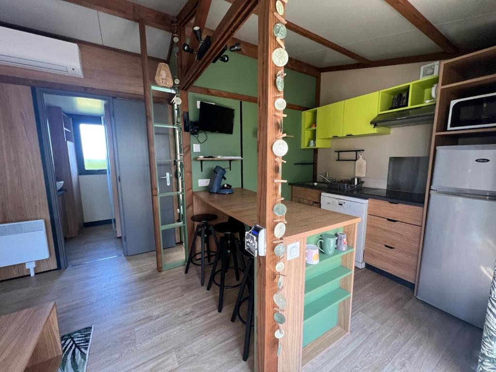 a kitchen with green and yellow walls and a wooden floor at 508 Mobilhome tout confort in La Teste-de-Buch