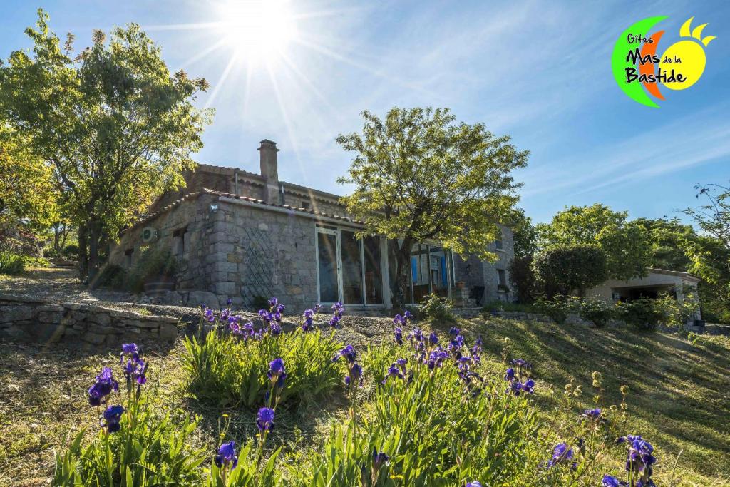 une vieille maison en pierre sur une colline avec des fleurs violettes dans l'établissement Gîte Pierre Blanche - Village De Gîtes, à Rosières