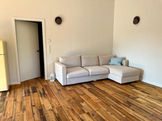 a living room with a white couch and wooden floors at okoTime - Studio mit Dachterrasse in Birkenwerder