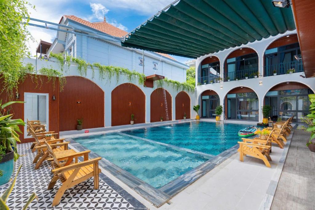 a swimming pool with wooden chairs and a building at Sea Villa 50 VTS - Villa Hồ Bơi Vũng Tàu Gần Biển - Phòng Karaoke Máy Lạnh in Vung Tau