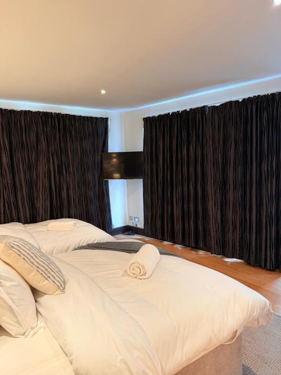 two beds in a bedroom with black curtains at Tower Bridge Apartments in London