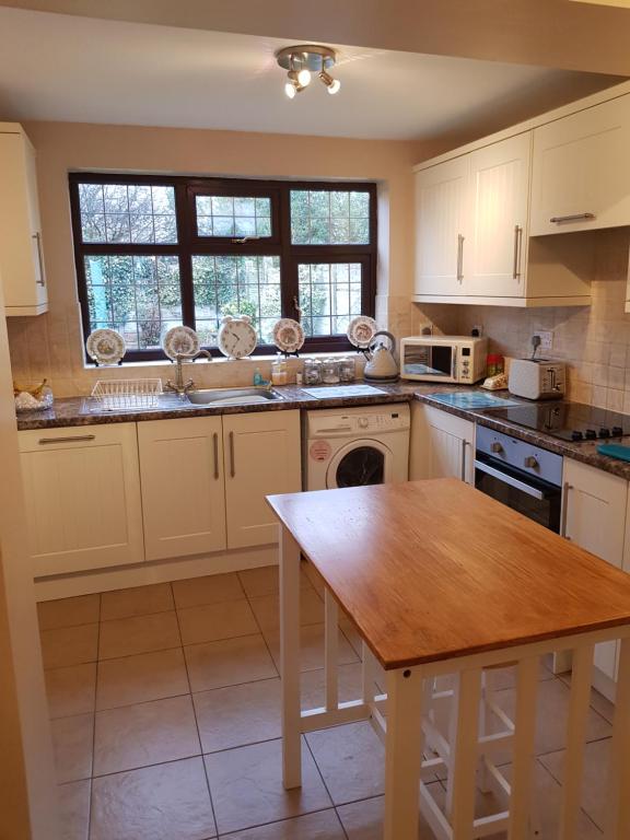 a kitchen with white cabinets and a wooden table at Single Bedroom in the main Bungalow in Wednesfield
