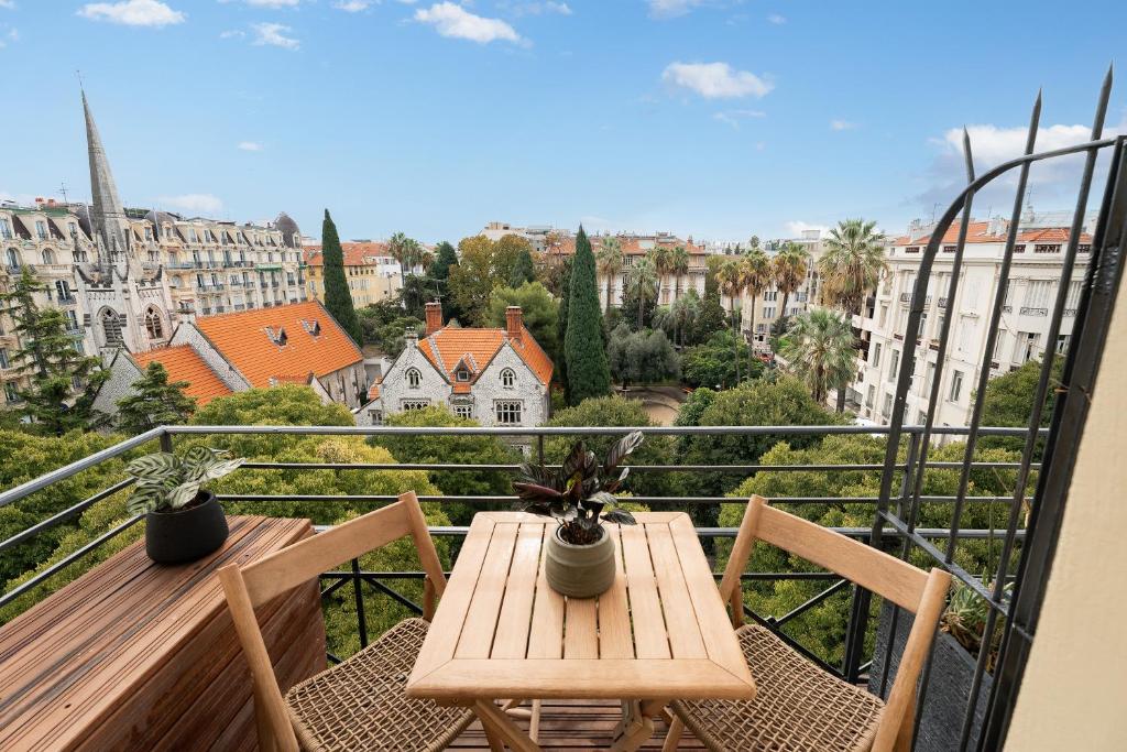a wooden table and chairs on a balcony with a view at Nice Renting - HUGO - Luxury Honeymoon Suite Terrace Park View Free Parking in Nice