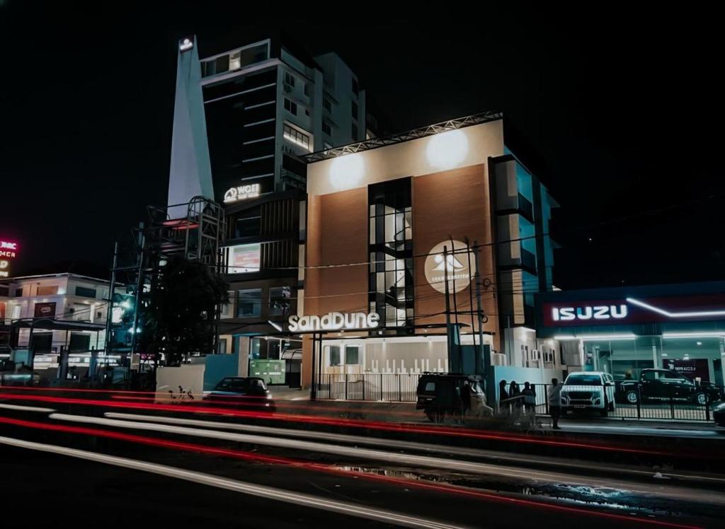 un edificio con un reloj al costado de él por la noche en SandDune Luxury Suites, en Ernakulam