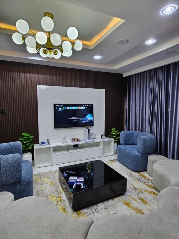 Una sala de estar con dos sillas y un televisor. en MOTF Apartments, en Okunola