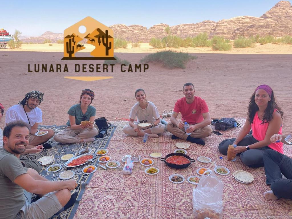 a group of people sitting around a picnic in the desert at Lunara Desert Camp in Wadi Rum