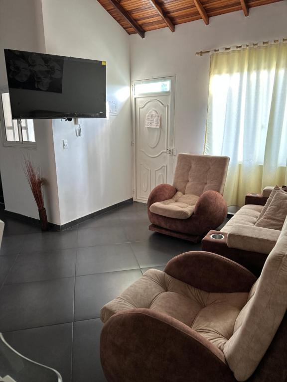 a living room with two chairs and a flat screen tv at Apartamento con vista a San Gil en excelente ubicación in San Gil