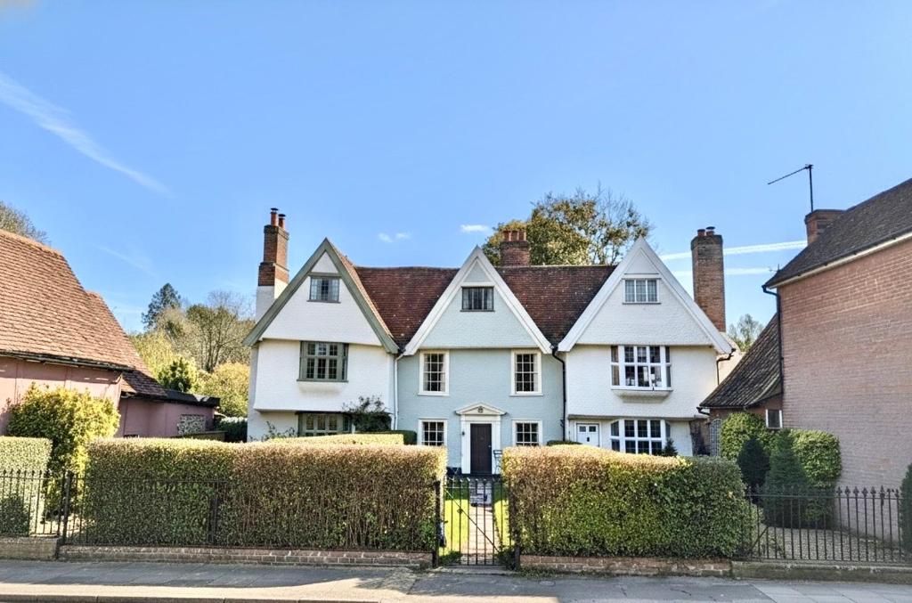 a white house with a fence in front of it at Manor Cottage in Cavendish