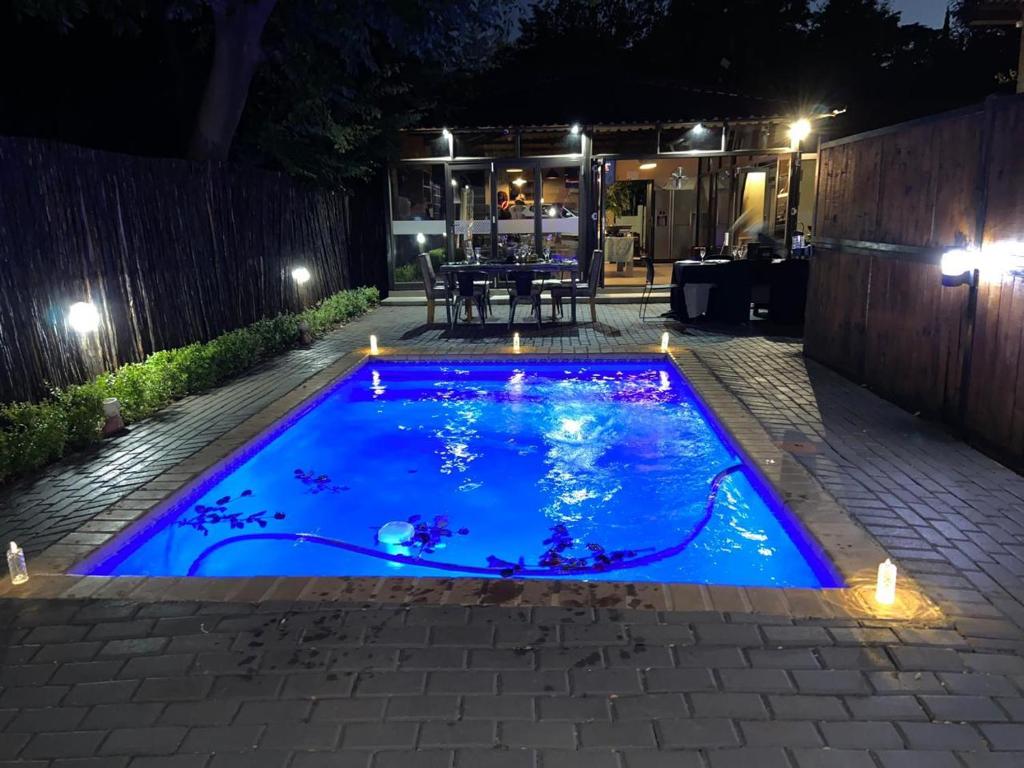 a swimming pool in the middle of a yard at night at 74 on retief Guesthouse in Potchefstroom