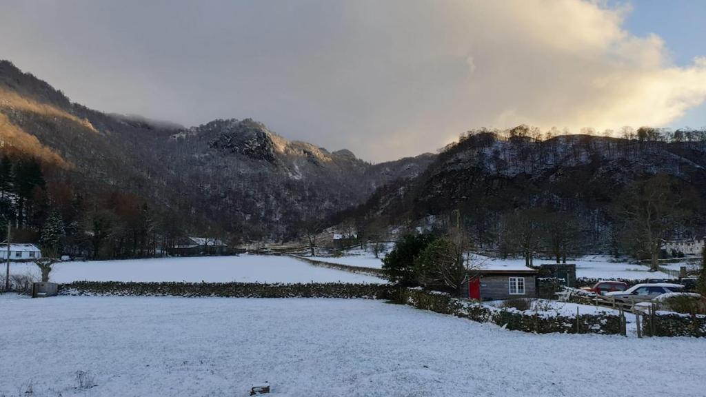 een veld bedekt met sneeuw met bergen op de achtergrond bij Mountain Lodge, Lake View, National Park in Borrowdale Valley