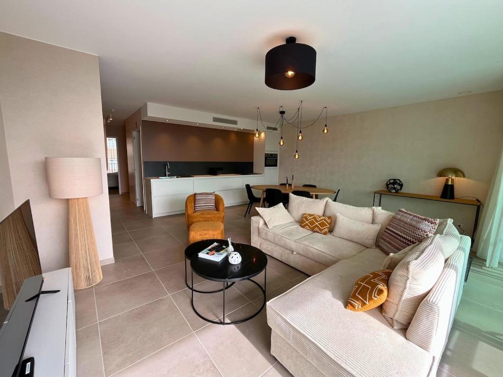 a living room with a couch and a table at Appartement moderne 2 chambres & 2 parking à Koksijde by La Conciergerie in Koksijde