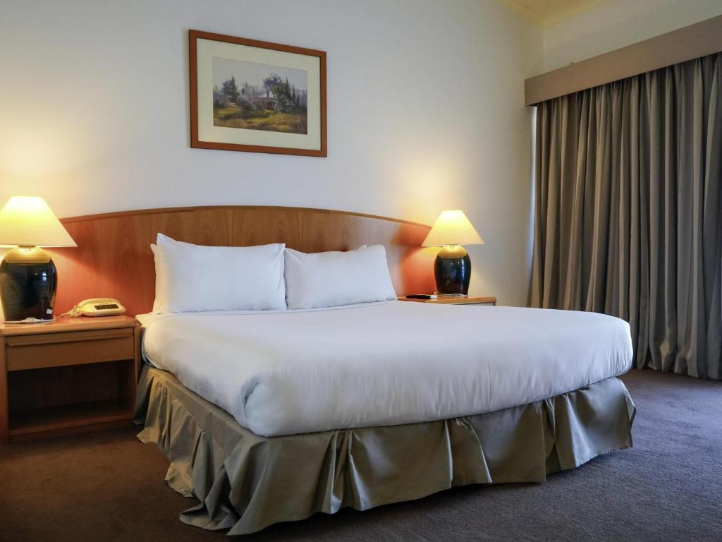 une chambre d'hôtel avec un grand lit et deux lampes dans l'établissement BreakFree Wirrina Cove, à Wirrina Cove