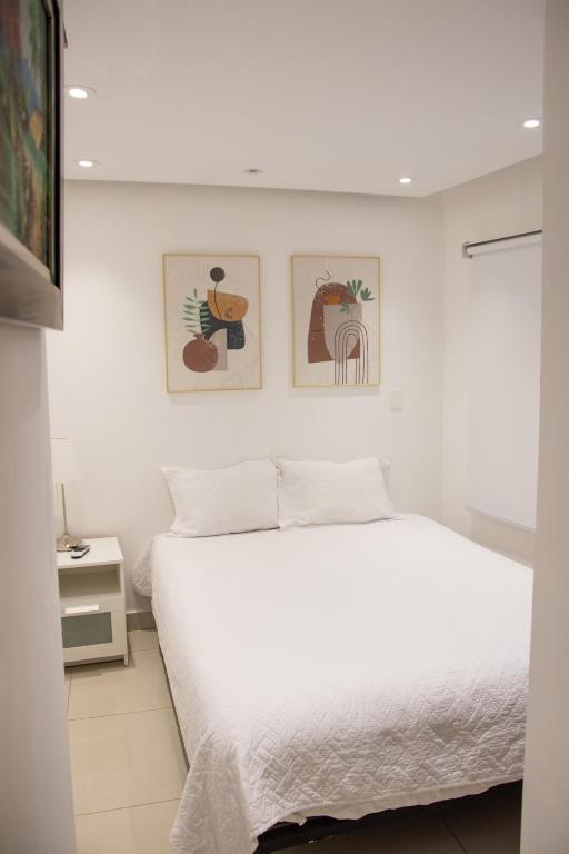 a bedroom with a white bed with three pictures on the wall at Casa de Nini in Santo Domingo