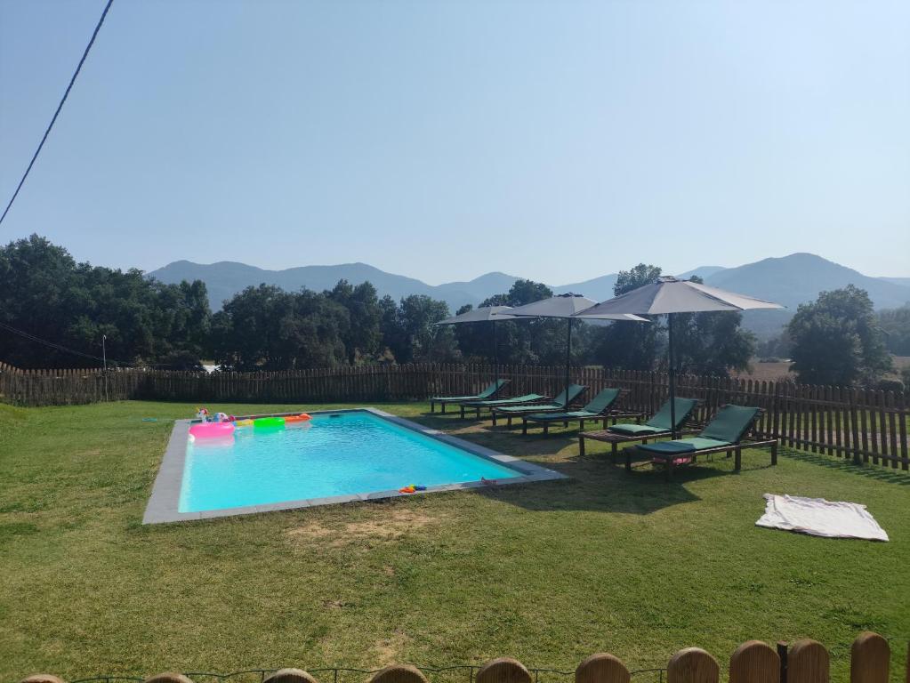 a swimming pool in a yard with benches and umbrellas at Casa rural Ca l'Antón in Sant Miquel de Campmajor