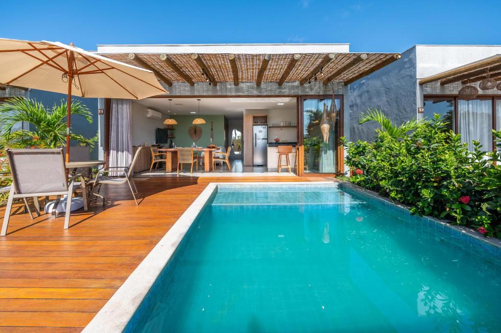a swimming pool with an umbrella next to a house at Bahia Soul - Casa Bambu - Barra Grande - Península de Maraú in Barra Grande