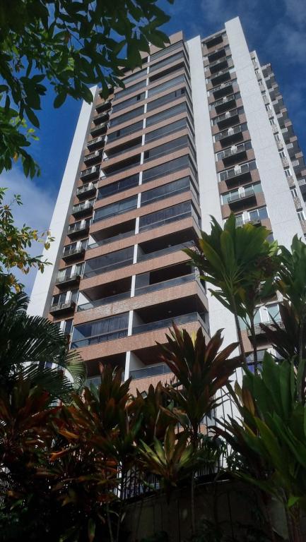 a tall building with palm trees in front of it at Quarto Vista Mar in Recife