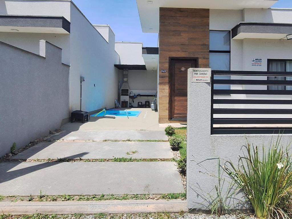 a house with a walkway leading to a door at Beach Residencial Prehenn 800 metros da praia agora com piscina in Itapoa