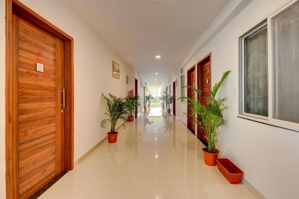 een hal met potplanten en een houten deur bij Hotel O Lotus Inn in Chinchwad