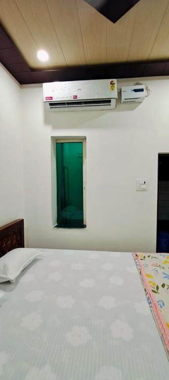 a room with a bed with a green window at Sakshi Seva Sadan Vrindavan Homestay & Restaurant in Vrindāvan