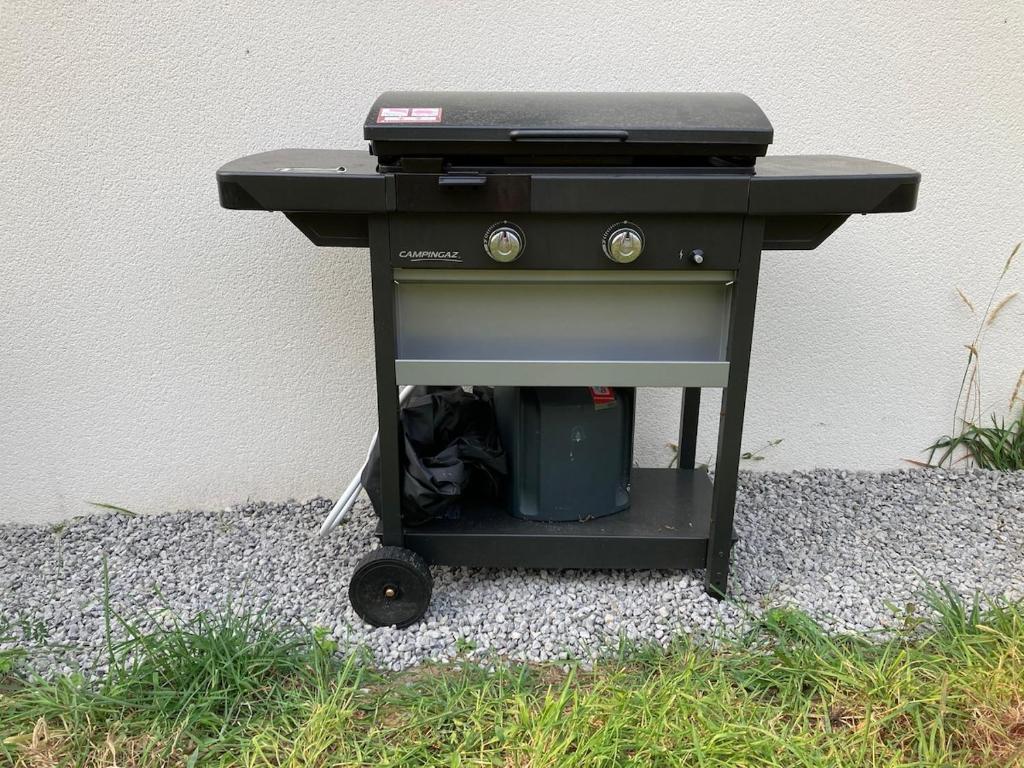 un barbecue posé sur le sol à côté d'un mur dans l'établissement Belle Villa Neuve 4 étoiles, à La Celle-sous-Gouzon