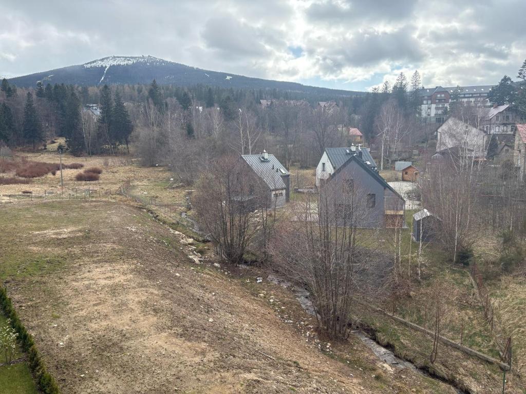 a field with houses and a mountain in the background at Belle View 212 Strumyk - Jacuzzi & Sauna in Szklarska Poręba