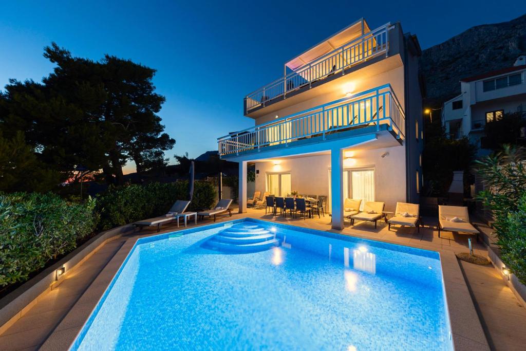 a villa with a swimming pool in front of a house at Villa ELLA ESTELLE with a heated pool, hot tub, sauna in Mimice