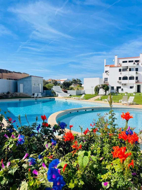 a swimming pool with flowers in front of a building at Casa Papillon in Sagres