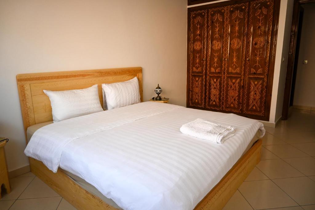 Un dormitorio con una cama grande con sábanas blancas. en Tiziri apartments, en Tamraght Ouzdar