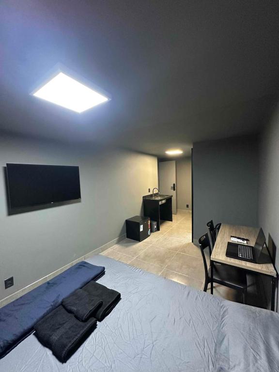 een slaapkamer met een bed, een bureau en een televisie bij Apartmento aconchegante no centro da capital in Brasilia