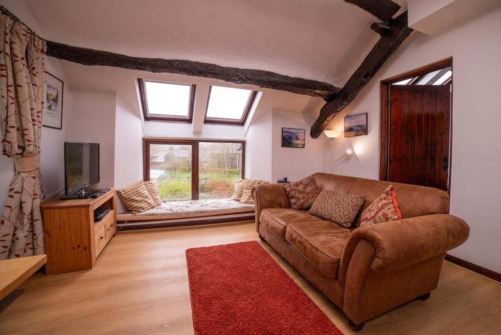 a living room with a couch and a tv at The Granary in Bampton