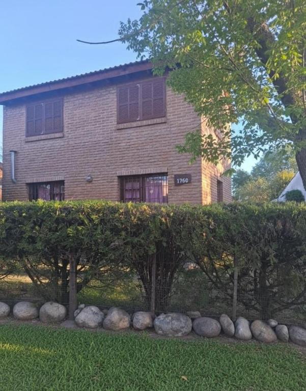 a house with a hedge in front of a building at La casa de Milac in Mina Clavero