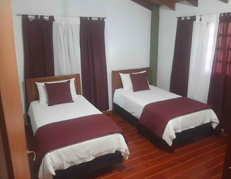 2 Betten in einem Zimmer mit roten Vorhängen in der Unterkunft La casa de Milac in Mina Clavero