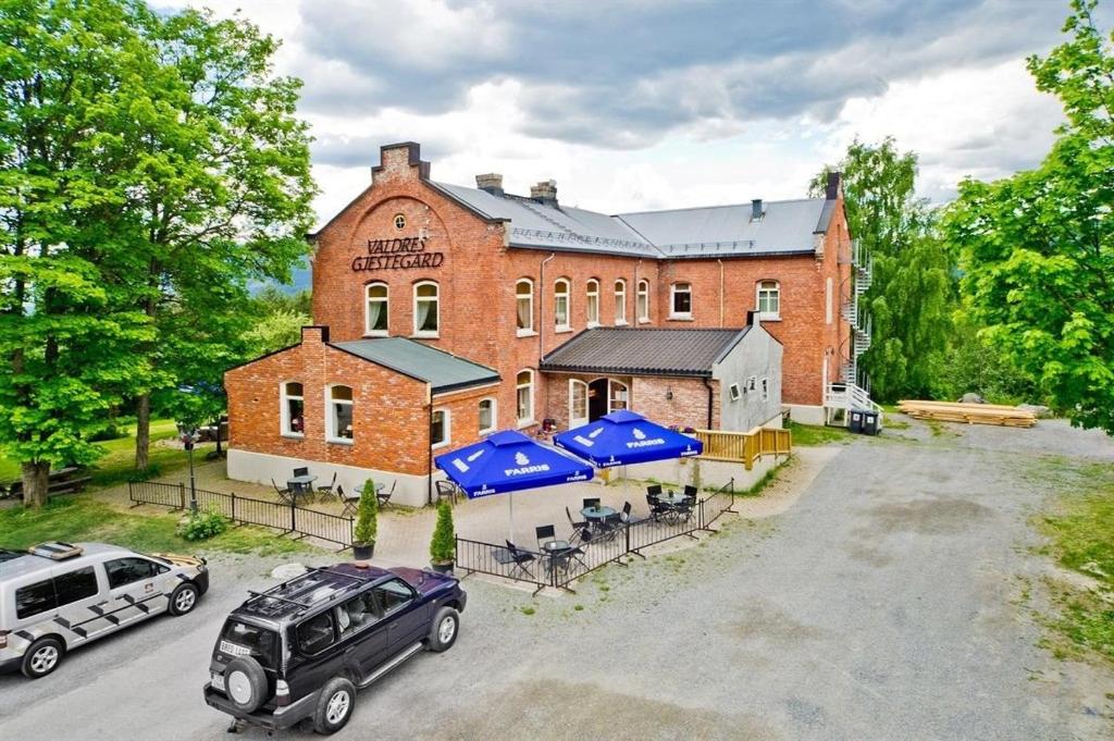a large brick building with two cars parked in front of it at Fengselet Gjestegård in Leira