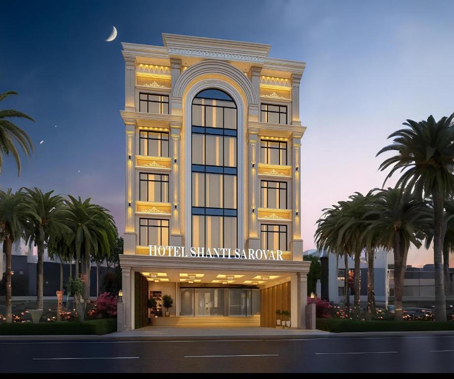 a hotel with palm trees in front of a building at Shanti Sarovar Haridwar in Haridwār