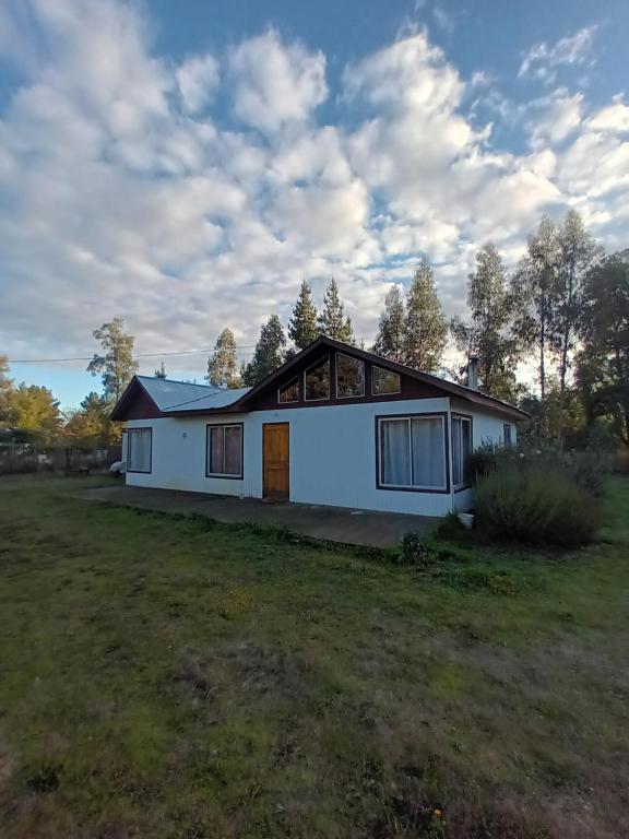 a house on a grassy field with trees in the background at Aves & árboles Casa 7p piscina y fogón in El Cerrillo