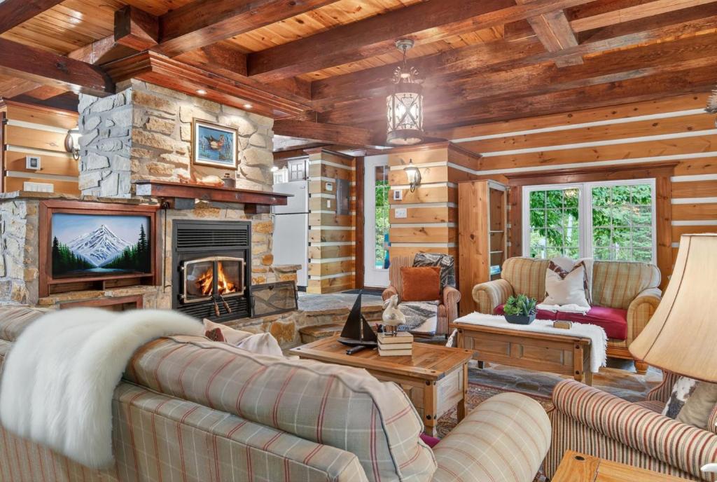 un salon avec cheminée dans une cabane en rondins dans l'établissement Domaine Rivière Sacacomie - Chalet l'Hirondelle, à Saint-Alexis-des-Monts