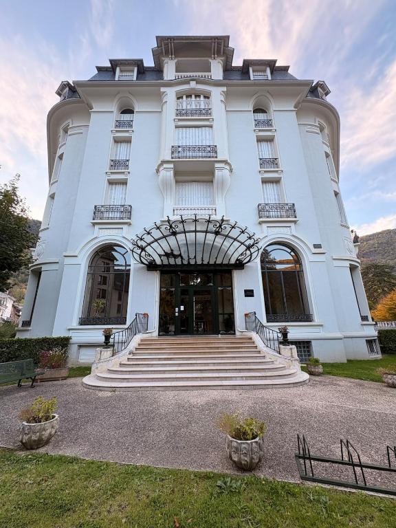 a large white building with stairs in front of it at Évasion tout confort au T3 bis Pyrénées Palace in La Celle-sous-Gouzon