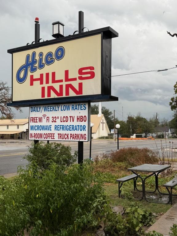 a sign for a hico hills inn with two benches at Hico Hills Inn in Hico