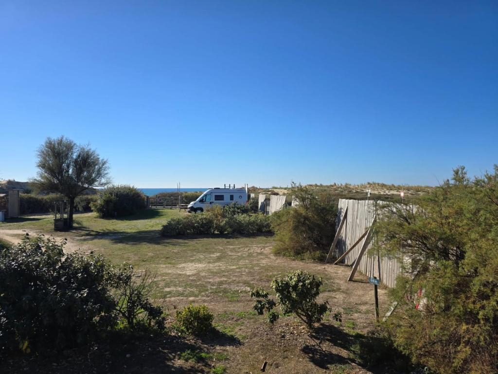 Blick auf einen Hof mit einem Wohnmobil und dem Meer in der Unterkunft Camping le soleil d'or Mobil Home in Montalivet-les-Bains