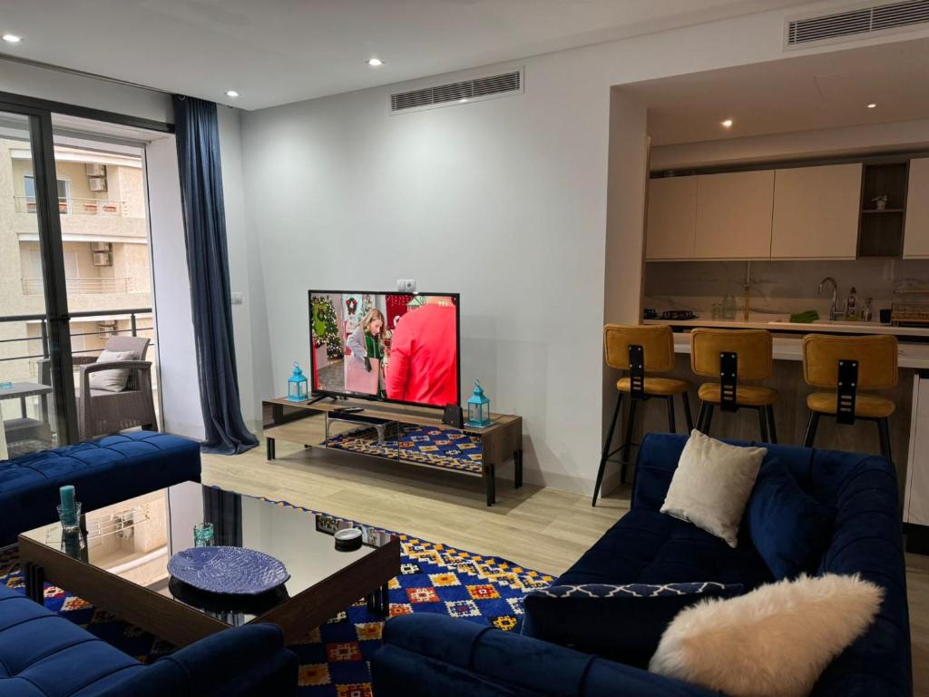 a living room with blue couches and a flat screen tv at Appartement de luxe in Sidi Daoud