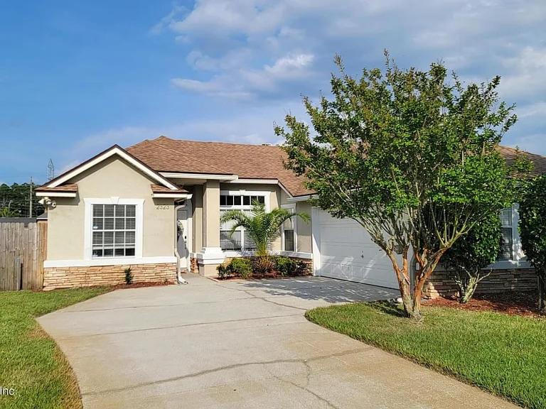 a white house with a tree in front of it at Minutes to Beach, Mayo Clinic, Hot Tub, King Bed, Free PPV in Jacksonville