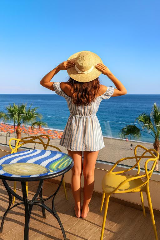 a woman in a hat is looking at the ocean at Blue Wave Apartment in Letojanni