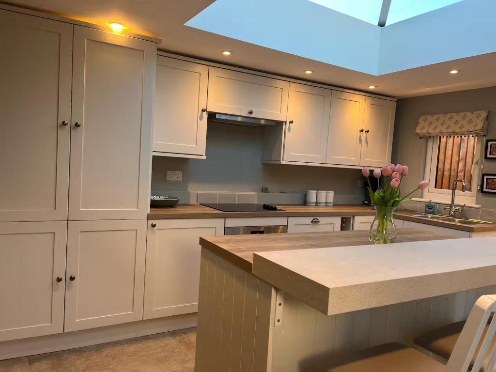 a kitchen with white cabinets and a vase of flowers at Charming cottage in Urchfont