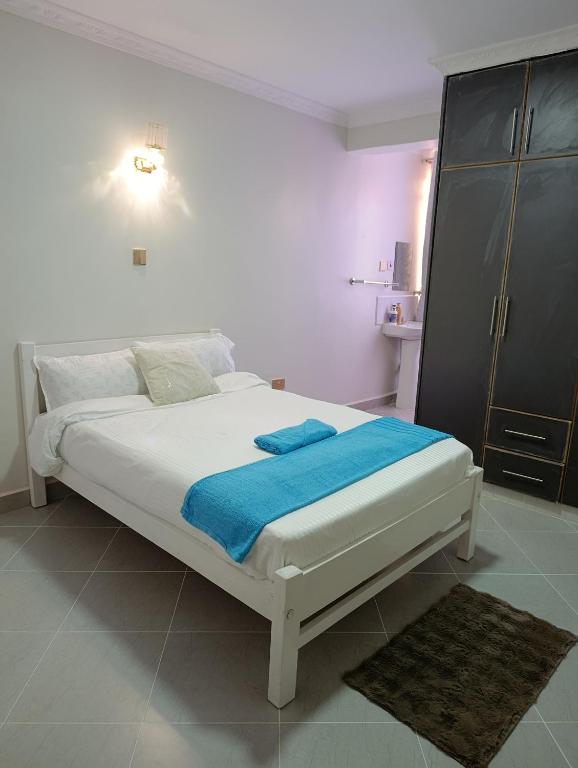 a bedroom with a bed with a blue blanket on it at Emraan Residence in Nakuru