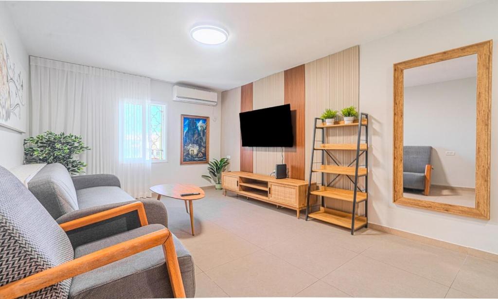 a living room with a couch and a tv and a mirror at דירת הפרימיום - 5 דקות נסיעה מהים in Ashqelon