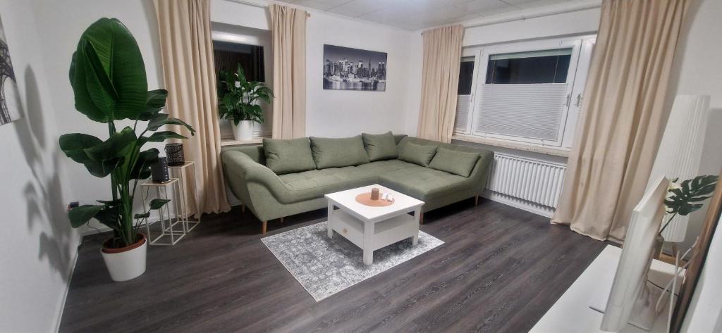 a living room with a green couch and a table at Ferienwohnung Lichtblick mit Terrasse in ruhiger Lage in Sulingen