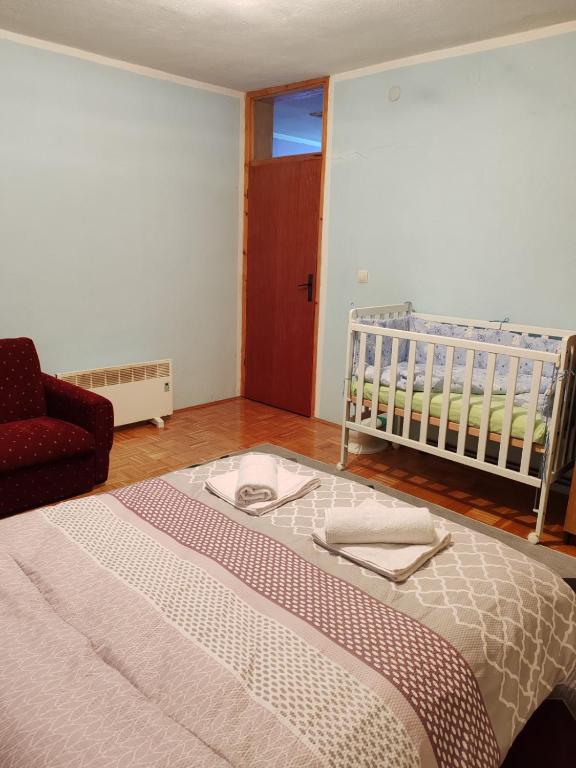 a bedroom with a bed and a crib and a chair at Apartman Dačo in Vlasenica