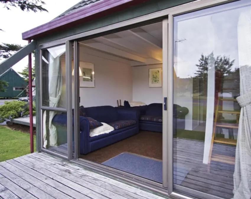 a sliding glass door on a deck with a couch at Ski Chalet Ohakune Alpine Village in Ohakune